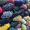 A close-up view of a large pile of multi-purpose paracord rope in various colors and textures.