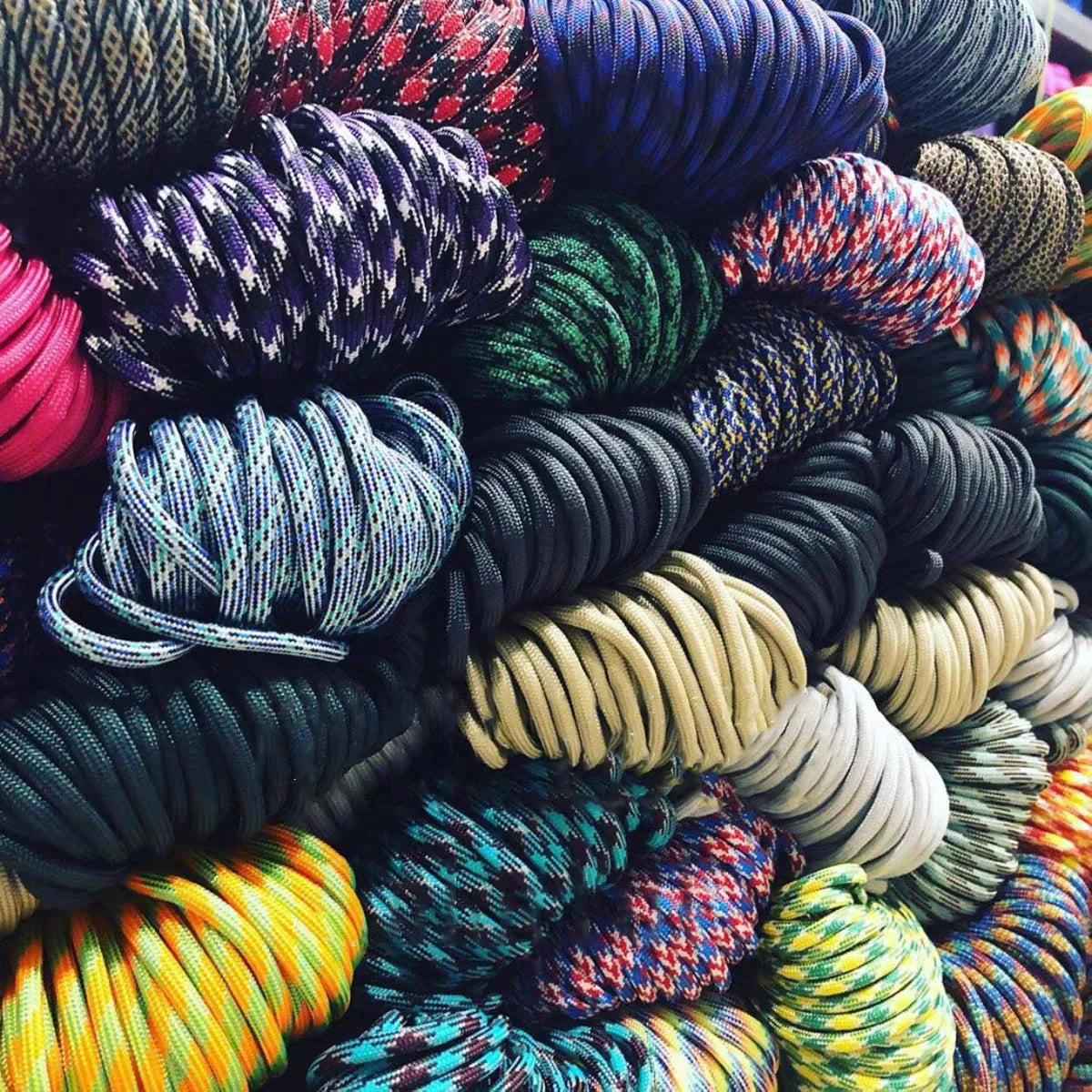 A close-up view of a large pile of multi-purpose paracord rope in various colors and textures.