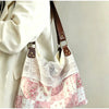 Sac à l'épaule patchwork floral rose pâle et blanc avec un surplis en dentelle et une sangle en cuir marron.