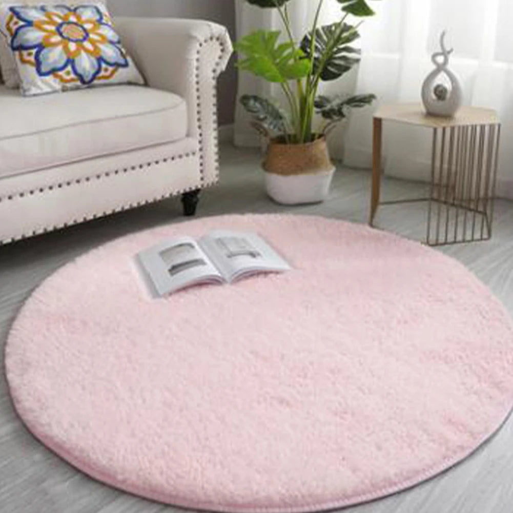 A round, pink, ultra-soft shaggy rug placed on a light gray floor in a living room setting.