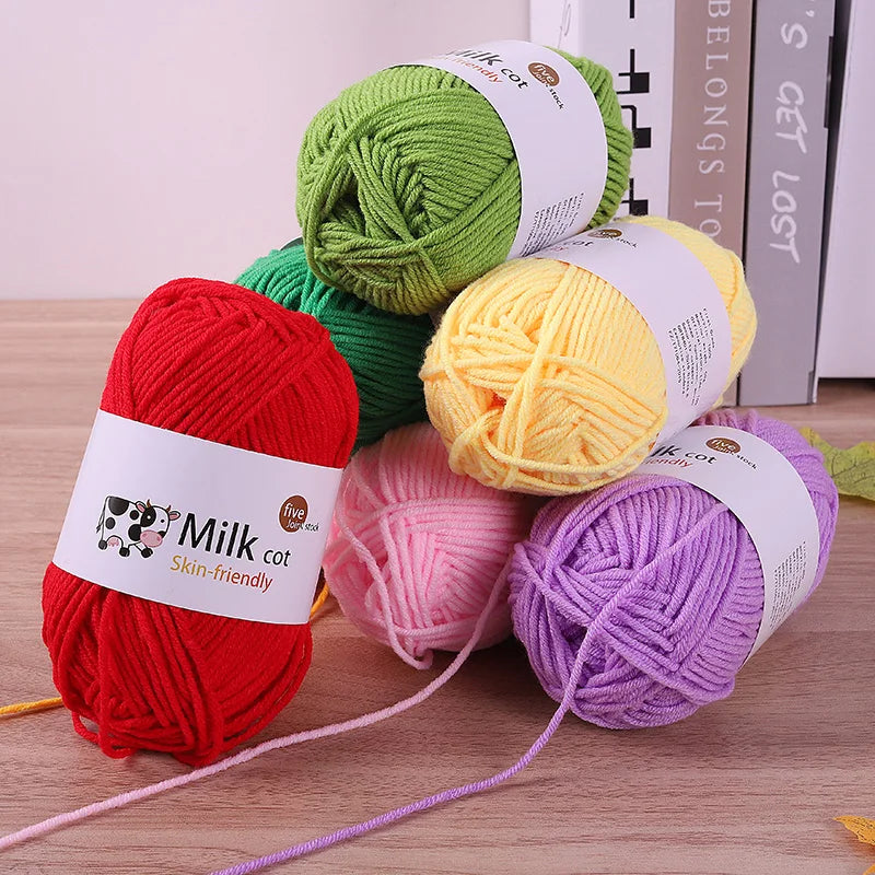 A collection of five skeins of colored acrylic yarn including green, yellow, red, pink, and purple wool for knitting and croc