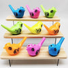 A collection of colorful plastic bird whistles in various shades including blue, pink, green, and orange displayed on wooden 