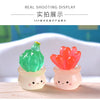 Two small, luminous succulent cactus miniatures in green and orange are displayed on a wooden surface.
