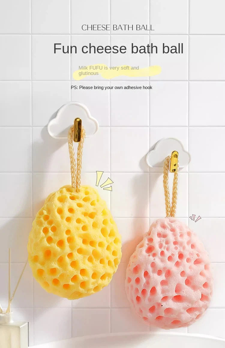 A yellow cheese bath ball and a pink cheese bath ball are hanging on a white tiled wall.