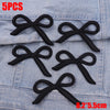 Five black embroidered bow iron-on patches displayed on a denim fabric background.