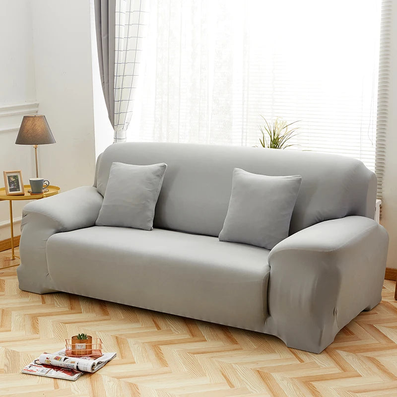 A light gray silky soft stretchable sofa cover for pet owners displayed on a living room floor.