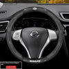Close-up view of a black Nissan steering wheel with a carbon fiber patterned grip and controls.