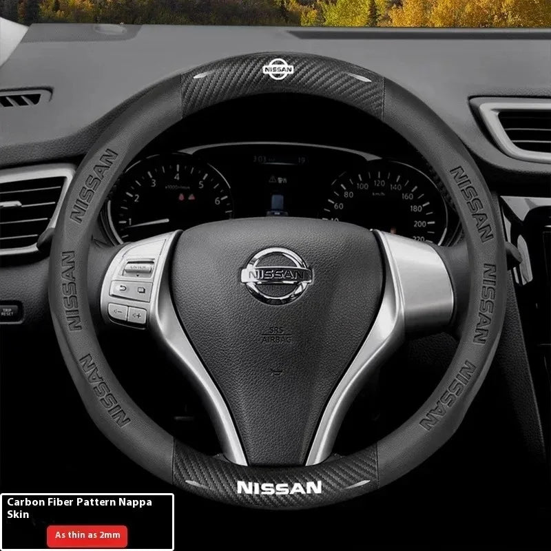 Close-up view of a black Nissan steering wheel with a carbon fiber patterned grip and controls.