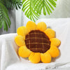 A bright yellow and brown sunflower shaped floor pillow resting on a white textured cloth.
