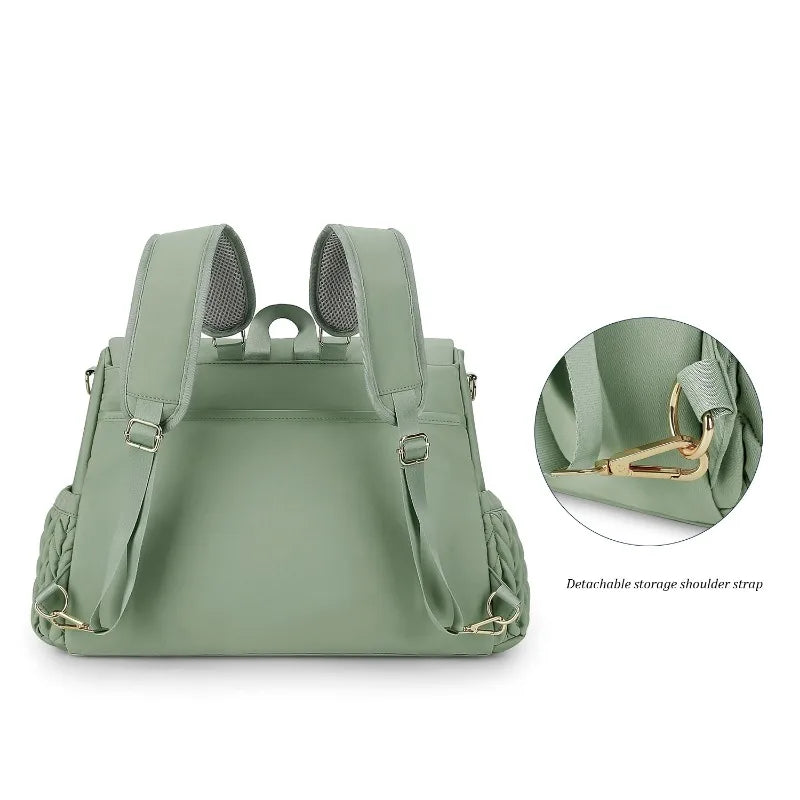 A light sage green diaper bag featuring detachable shoulder straps and storage pockets.