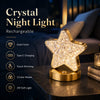 A gold-finished star-shaped rechargeable night light with touch dimming and three color modes resting on a dark surface.
