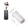 A silicone mold with a cylindrical body and a threaded opening, shown next to dried floral stems.