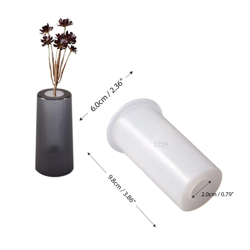 A silicone mold with a cylindrical body and a threaded opening, shown next to dried floral stems.