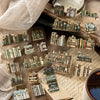 A collection of die-cut stickers and miniature books arranged on a wooden surface with a magnifying glass.
