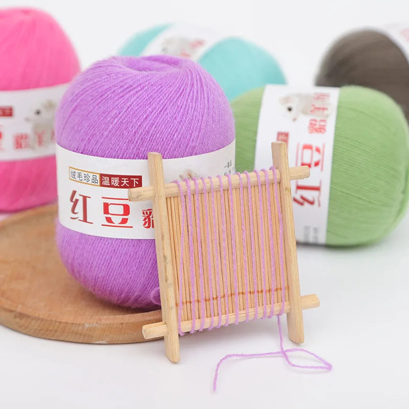 A purple yarn skein next to a wooden bamboo knitting needle and other colored yarns.