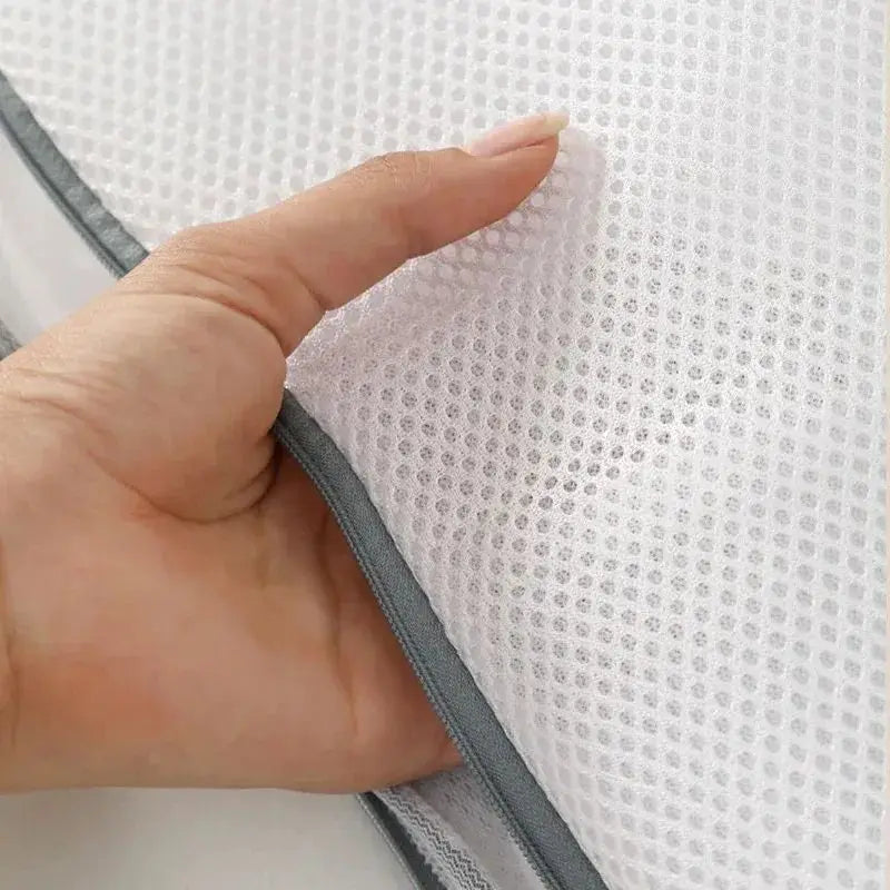 A hand is touching a white fine mesh laundry bag for delicate underwear, showing the texture and fabric.