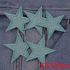 A set of five teal glitter star iron-on embroidered patches placed on a denim fabric background.