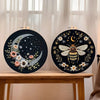 Black embroidery art featuring a golden butterfly and silver crescent moon on a circular canvas