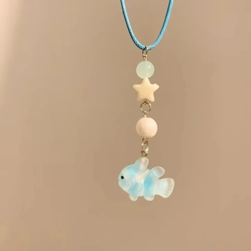 A delicate turquoise beaded necklace featuring a starfish and a small light blue fish pendant.