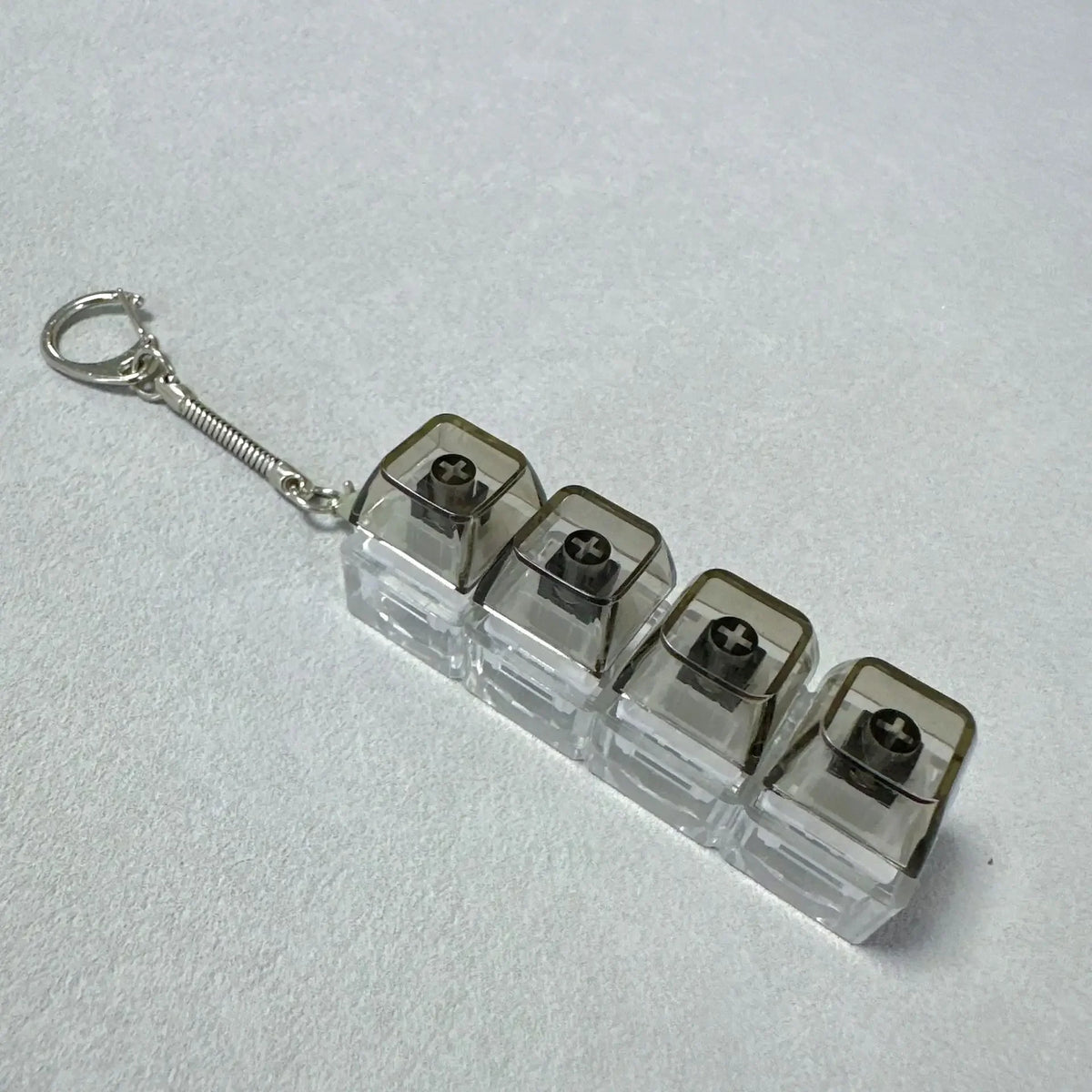 A clear plastic LED light-up keyboard keychain fidget toy with a silver keyring.