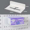 A white desktop pegboard organizer with shelves and hooks is shown in a close-up view.
