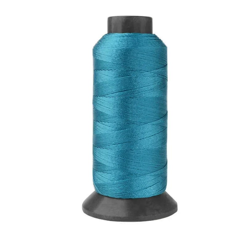 A spool of teal blue heavy-duty nylon sewing thread for upholstery and denim.