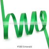Green satin ribbon in an emerald color coiled and draped against a white background.
