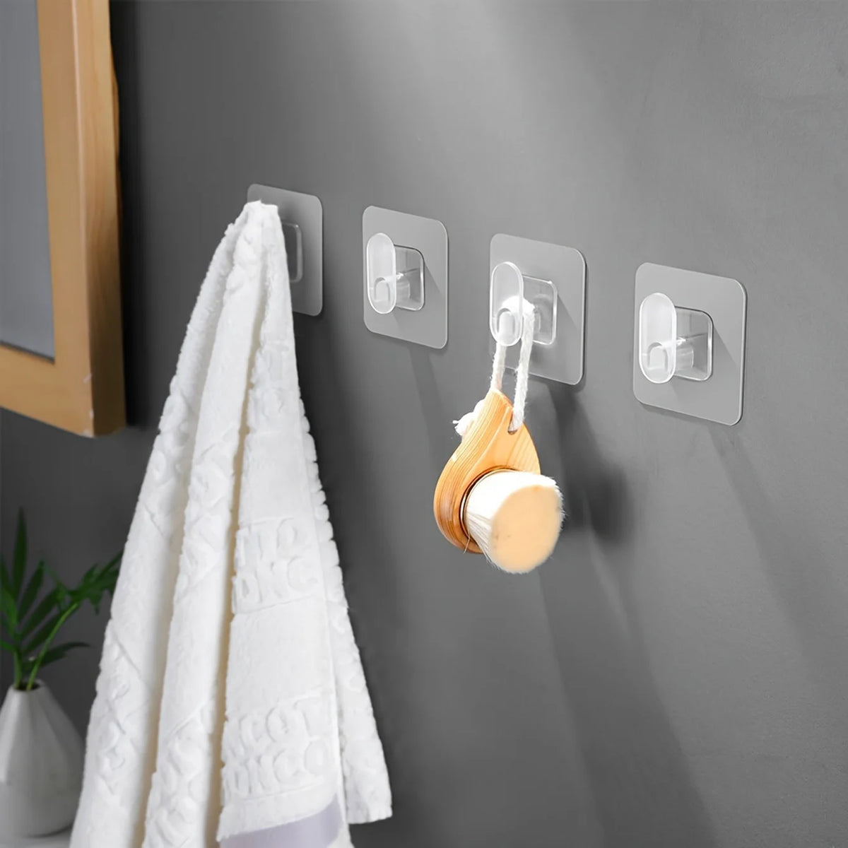 A white towel hangs on a gray wall featuring three silver adhesive hooks for heavy-duty organization.