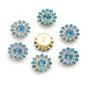 A collection of twelve round, blue and clear crystal flower rhinestones on a gold-toned backing.