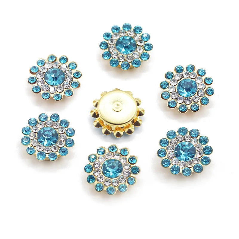 A collection of twelve round, blue and clear crystal flower rhinestones on a gold-toned backing.