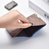 A hand opens a brown leather compact double-fold wallet with blue accents on a white surface.