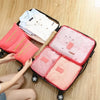 A black rolling suitcase is open, displaying six pink and white laundry pouches packed with clothing.