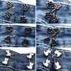Close-up of various silver and gold no-sew adjustable buttons for tightening jeans, including floral, heart, and cat designs.
