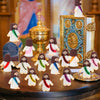 A collection of mini Jesus figurines in various colors and outfits displayed on a wooden surface.