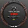A brown carbon fiber and leather steering wheel cover for a Mazda vehicle.