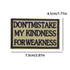 A rectangular embroidered patch with dark blue text on a tan background that reads DON'T MISTAKE MY KINDNESS FOR WEAKNESS