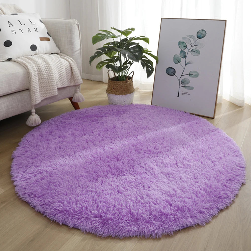 A round, purple, ultra-soft shaggy rug placed on a light wood floor in a living room setting.