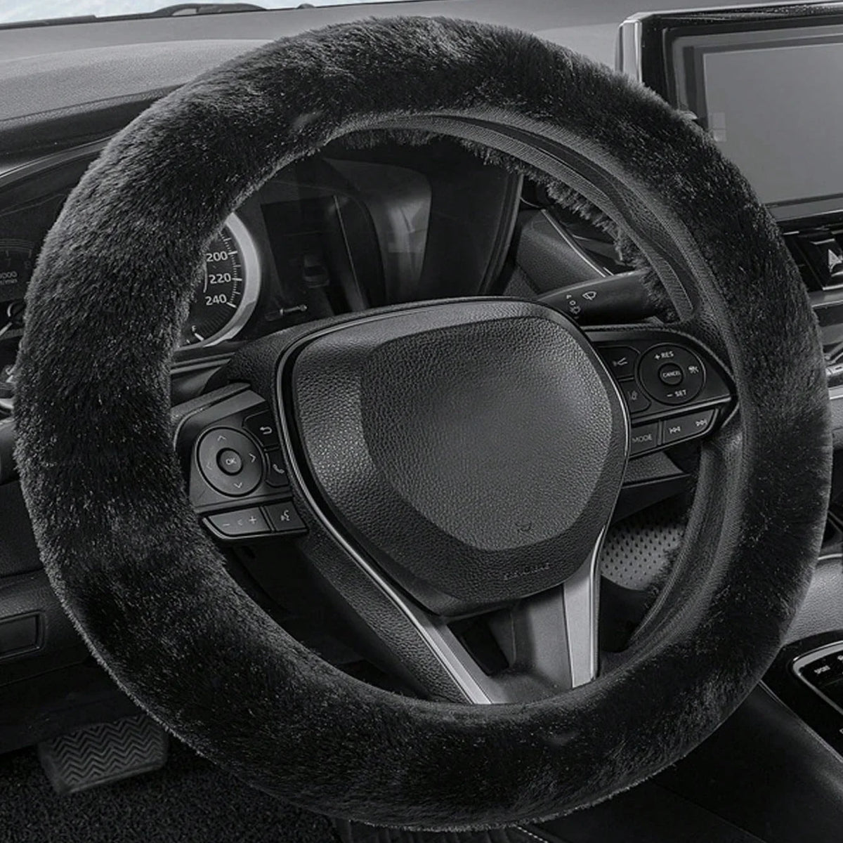 A close-up view of a black winter plush steering wheel cover on a car's steering wheel.