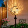 A solar owl garden light featuring a crescent moon silhouette and a bird design mounted on a wooden fence.