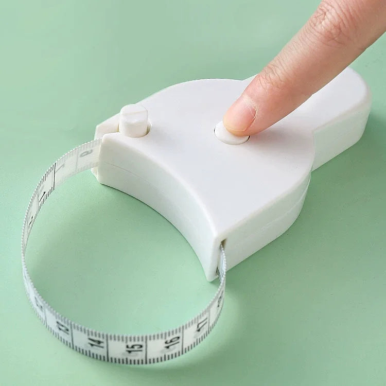 A hand is holding a white retractable body measuring tape against a white plastic device.