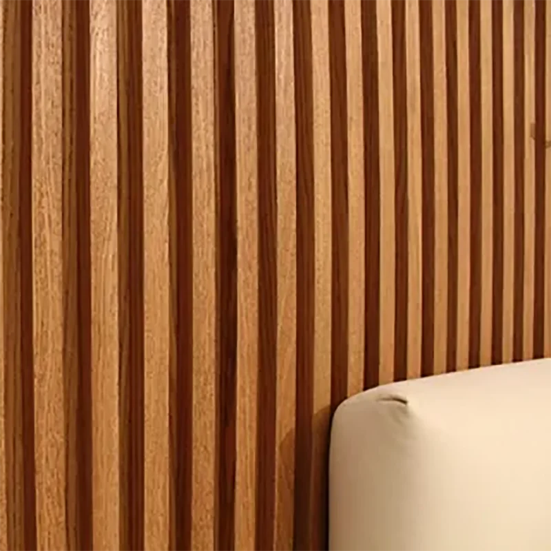 Close-up of vertical wood-grain striped peel-and-stick wallpaper on a wall next to a white cushion.
