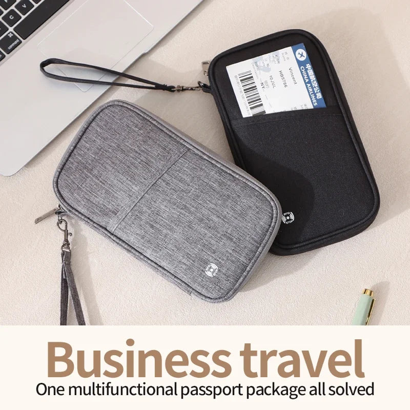 A black and gray multifunctional passport package organizer lying on a light surface next to a laptop.