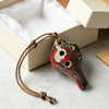 Handcrafted ceramic pendant ocarina with six holes, featuring red and white glaze, resting in a light box.