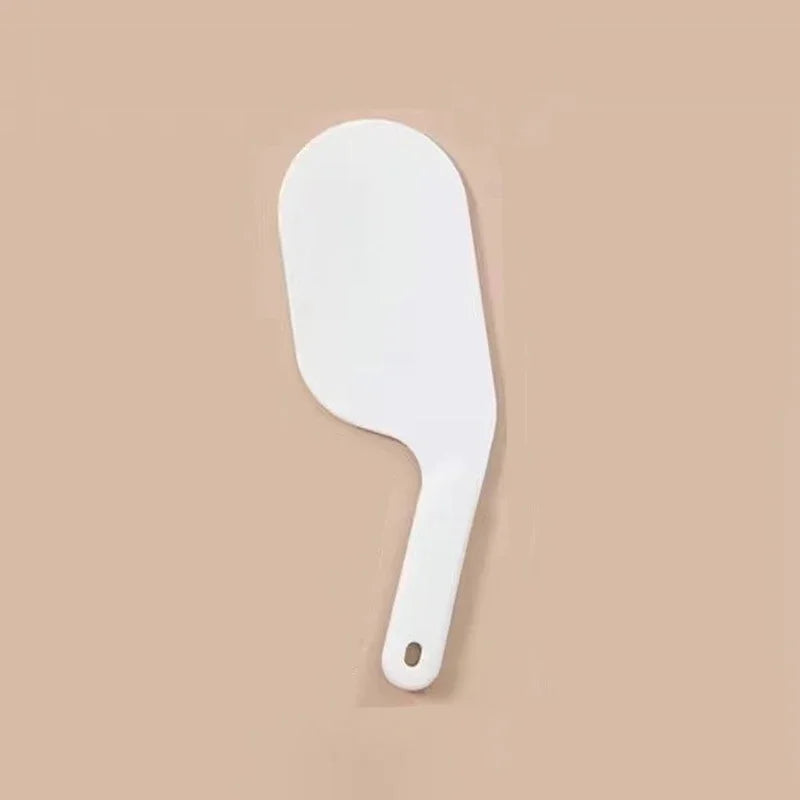 A white, ergonomic bed sheet tucking tool with a curved handle is shown against a beige background.