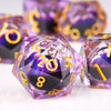 A close-up of a purple liquid resin die with gold numbers and a dragon eye design resting on a white surface.