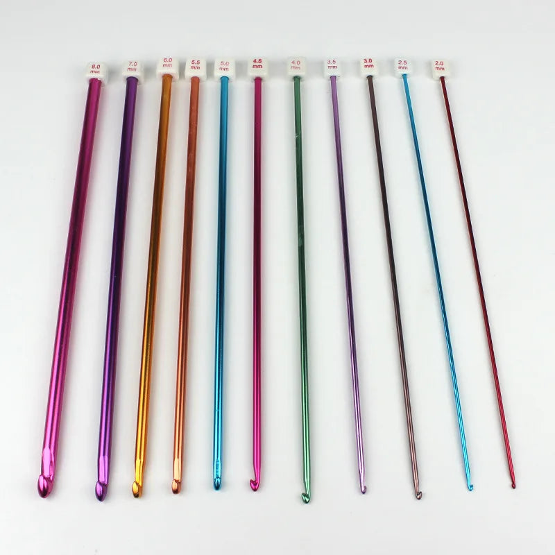 A set of 23 Tunisian crochet hooks with various colored bamboo cables arranged in a row.