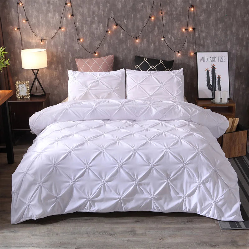 White queen comfort bedding set featuring a quilted comforter and pillows against a gray wall.