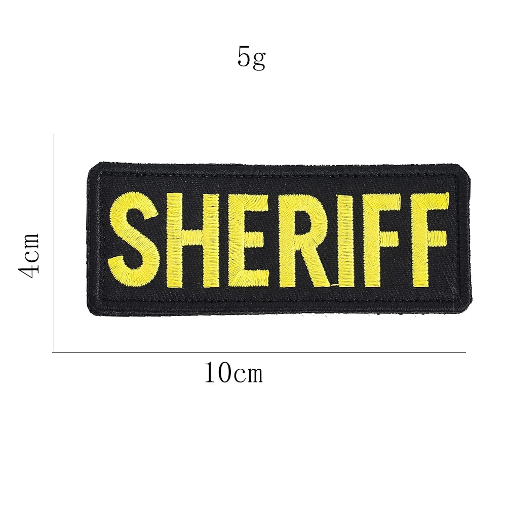 A black embroidered patch with yellow text spelling SHERIFF and a 5g tag, measuring 4cm by 10cm.