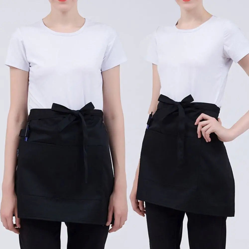 A woman models a black half apron with pockets for kitchen use.