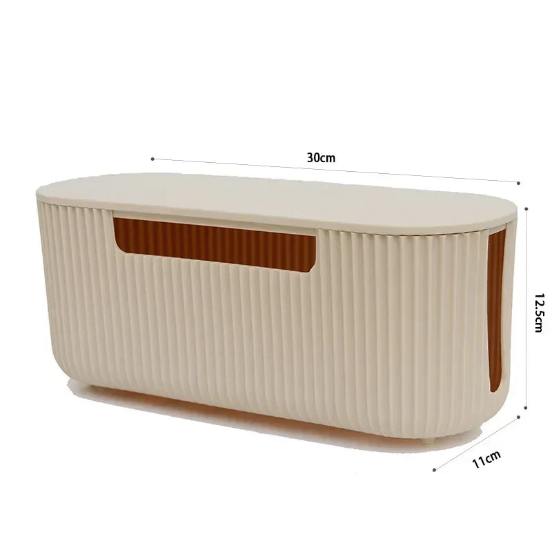 A beige cable management box with vertical ridges and a slanted opening, measuring 30cm long and 12.5cm high.